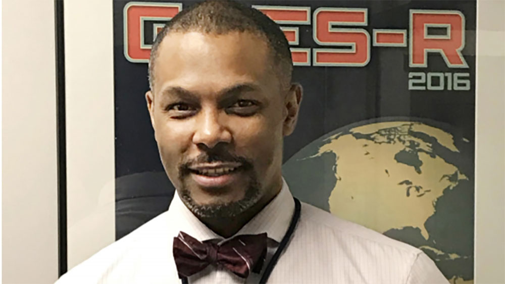 headshot of Kevin in front of a GOES-R launch poster